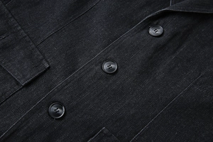 Détail du tissu denim à chevrons haut de gamme avec boutons noirs brillants sur le blazer