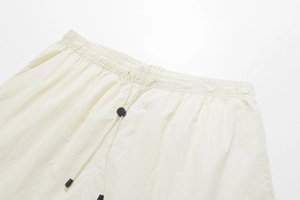 Detail of elastic waistband and adjustable drawstring toggle on cream sports shorts