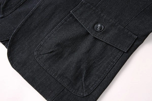 Détail du tissu en sergé bleu marine avec une grande poche et un bouton noir brillant