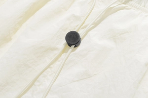 Detail of cream shorts featuring adjustable drawstring with black plastic cord lock toggle