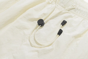 Detailed close-up of beige drawstring shorts showing elastic waistband and cord lock