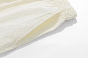 Close-up of elastic waistband and pocket detail on cream quick-dry casual shorts