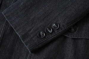 Détail macro du blazer en denim pour homme avec motif chevrons et boutons de manchette