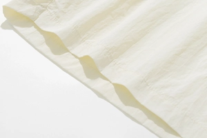 Detailed close-up of light beige quick-dry fabric showing double stitching on the hem