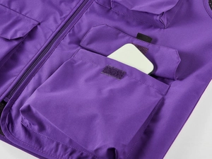 Détail du gilet utilitaire violet montrant de grandes poches à velcro et un rangement