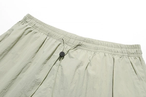 Detail of light green sports shorts featuring elastic waistband and black drawstring toggle