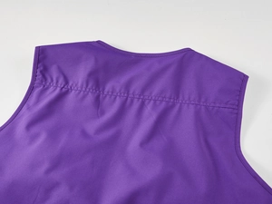 Détail des coutures renforcées de l'épaule et de l'encolure sur un gilet de photographe violet