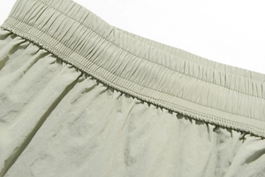 Close-up of the elastic waistband and fine stitching on light green quick-dry shorts