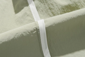 Macro detail of breathable sage green fabric with white decorative webbing on shorts