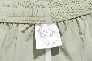 Detail shot of elastic waistband and 100% nylon wash label on green athletic shorts