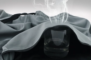Close-up of gray sports shorts fabric showing high breathability with steam test