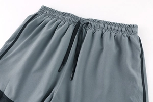 Detail of grey athletic shorts featuring elastic waistband and black adjustable drawstring