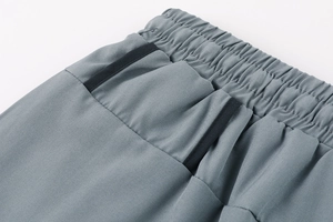 Detail of grey sports shorts featuring elastic waistband and black-trimmed side pocket