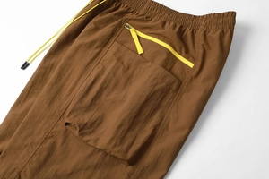 Detail of cargo shorts with bright yellow zipper pocket and matching drawstring waist