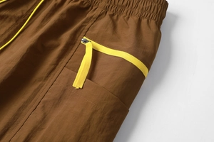 Detailed macro view of brown cargo shorts featuring elastic waist and yellow drawstring