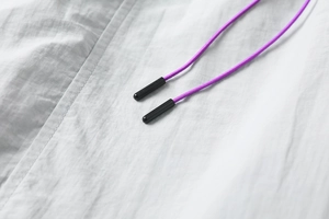 Macro shot of light gray cargo shorts featuring vibrant purple drawstrings with black tips