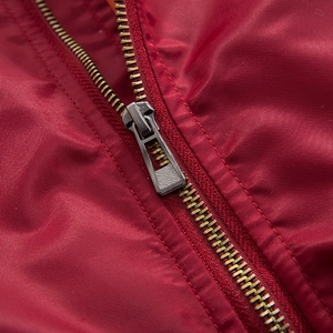 Detailed macro view of durable brass metal zipper on red bomber jacket fabric