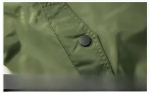Detail view of olive green bomber jacket featuring side pockets with matte black snap buttons