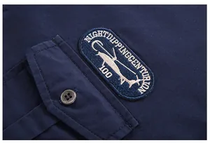 Detail of navy cotton shirt showing a chest pocket with helicopter embroidery and button