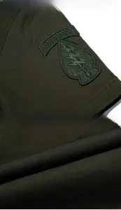 Detail van een legergroen katoenen overhemd met tactisch airborne borduursel en stoftextuur