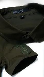 Detail van een legergroen katoenen werkoverhemd met neklabel en geborduurde mouwpatch