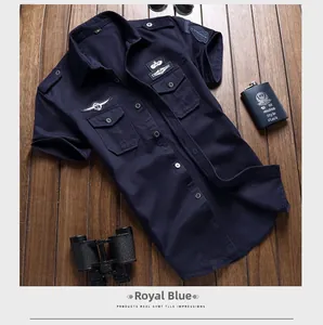 Camicia tattica blu reale a maniche corte con toppe militari su sfondo di legno scuro
