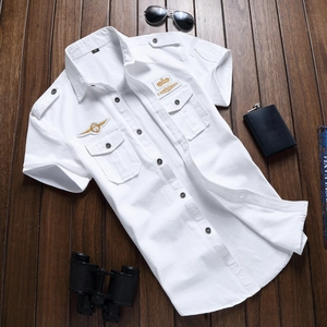 Camicia bianca a maniche corte da uomo con distintivi militari su fondo di legno