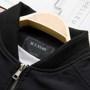 Close-up of black baseball jacket collar with ribbed texture and silver metal zipper