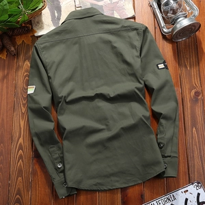 Detail view of military green cotton shirt back with sleeve patches on wood background