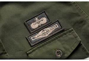 Dettaglio di camicia cargo verde militare con distintivi ricamati e bottoni in metallo