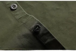 Dettaglio ravvicinato dei bottoni metallici vintage su camicia in twill di cotone oliva