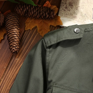 Detailed macro view of olive green cotton shirt shoulder epaulet and metallic button