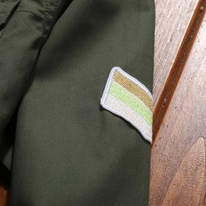 Close-up of military green cotton cargo shirt sleeve with embroidered stripe patch detail