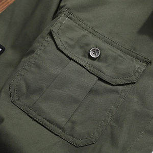 Detail of army green cotton work shirt featuring durable twill fabric and buttoned pocket