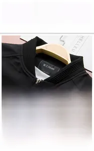 Detail of a black slim fit jacket featuring a ribbed stand collar and smooth metal zipper