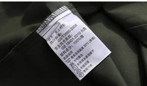 Detailed close-up of the 100% cotton washing label on olive green cargo shirt
