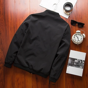 Men's black lightweight pilot bomber jacket with ribbed cuffs and sleeve pocket on wood