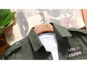 Detail of army green cotton work shirt featuring shoulder epaulettes and chest embroidery