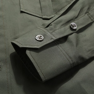 Detailed close-up of buttoned cuff on olive green military style work shirt with twill texture