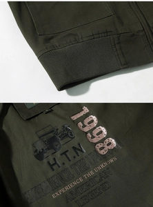 Macro detail of olive green cargo jacket showing rib-knit hem and vintage industrial print
