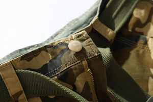 Detail of cargo shorts waist featuring metal zipper, button, and camouflage cotton twill