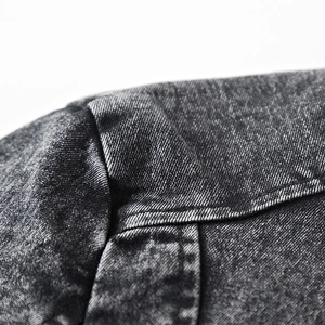 Détail d'une veste en jean noire montrant la texture sergée et les coutures vintage lavées