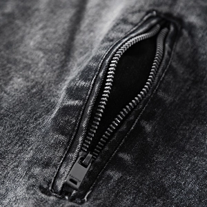 Détail macro d'une fermeture éclair en métal noir mat sur tissu denim délavé gris