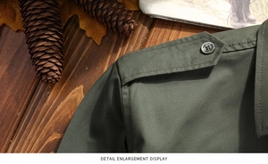 Detail enlargement showing shoulder epaulets with button on military green cotton shirt