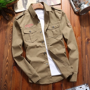 Men's khaki military work shirt with double pockets and vintage patches on wood background