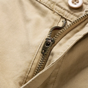 Primer plano de la cremallera metálica y el botón de resina en los pantalones cortos caqui