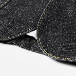 Détail d'une veste en jean noire avec doubles surpiqûres orange et texture de denim
