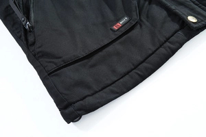 Dettaglio della tasca del parka nero con bottone dorato ed etichetta logo in gomma