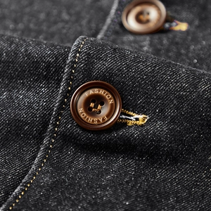 Vue détaillée du tissu denim foncé avec bouton de mode et coutures jaunes contrastées