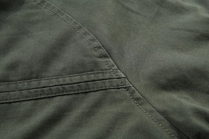 Dettaglio ravvicinato del tessuto twill verde militare e doppia cucitura sulla giacca